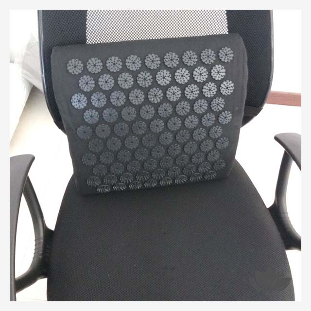 Coussin d'acupression Lowbar posé sur contre un dossier de chaise de bureau